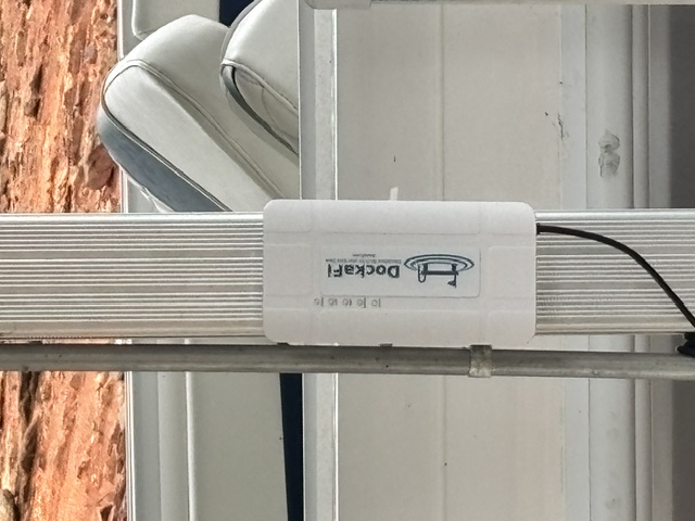 DockaFi mounted on a dock post with a boat nearby